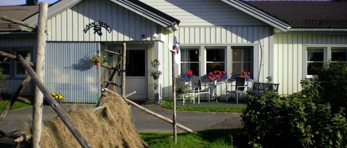 Rönngårdens äldreboende. Tagen sommartid med höhässja, blommor och buskar framför ingången.